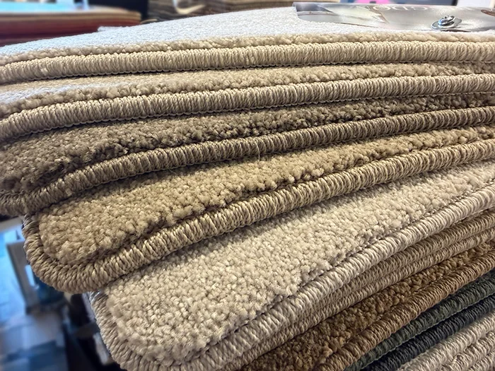 Stack of neutral carpet samples finished with stitched yarn whipping